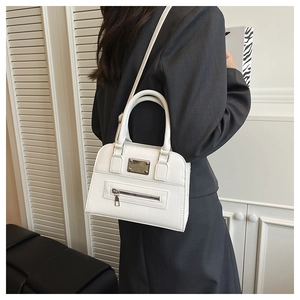 Detailed view of a white PU leather Boston bag with metal plate and zipper on a model