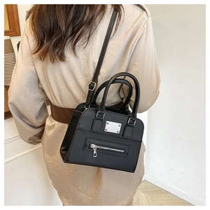 Detail of black matte leather handbag with silver metal plate and zipper for daily commute