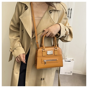 Detail view of ginger leather tote bag featuring a front zipper pocket and silver metal accent