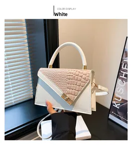 Detail view of white crossbody bag with crocodile texture and golden metal twist lock