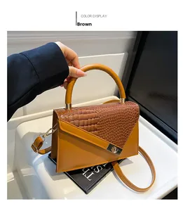 Detail of brown faux crocodile leather handbag with metal buckle and shoulder strap