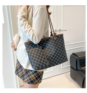 Close-up of a checkered tote bag with brown leather straps and matching pouch