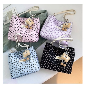 Flat lay of tote bags in four colors with bow patterns and plush bear charms