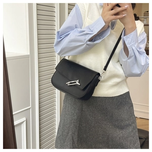Close-up of a black leather crossbody bag featuring a unique silver T-lock metal buckle