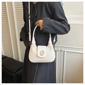 Detail of white woven texture handbag featuring a gold metallic M logo and leather handle
