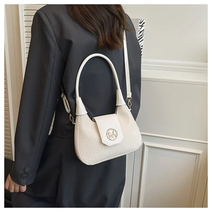 Close-up of a white woven semi-circle handbag with a golden M-logo clasp and chain