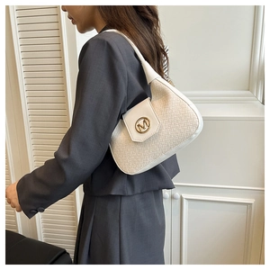 Detailed side view of beige woven handbag with gold M logo on grey suit model