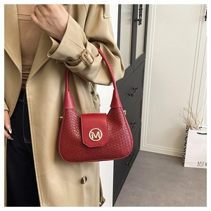 Detailed view of red woven handbag with gold M buckle on a trench coat model