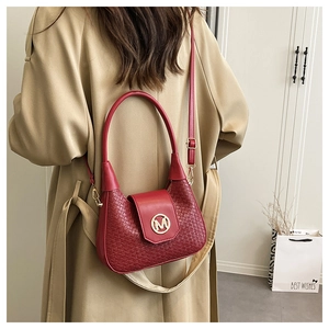 Detail of burgundy woven texture handbag with golden M logo and adjustable strap