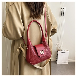 Detalle de bolso de mano tejido rojo con logo M dorado usado por una modelo