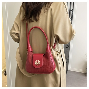 Detailed view of red woven texture shoulder bag with golden M metal buckle and leather flap