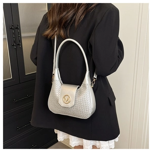 Detail of silver woven shoulder bag with golden M metal buckle on a minimalist model look