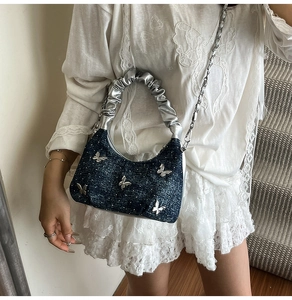 Détail du sac nuage en denim bleu avec papillons argentés et bandoulière en chaîne