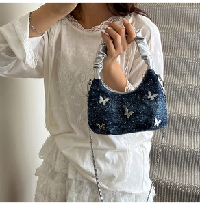 Détail du sac seau en denim avec boucle papillon argentée et paillettes scintillantes