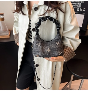 Détail du sac croissant gris foncé avec motifs papillon en métal et anse plissée