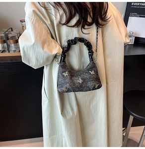 Détail du sac hobo gris avec breloques papillon en métal et anse noire à fronces
