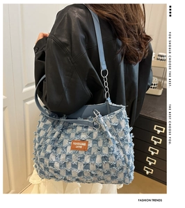 Detail of denim checkerboard bag showing frayed edges, leather tag and chain strap