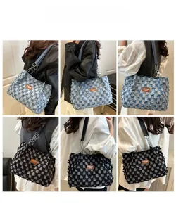 Detail of checkered denim tote bag featuring fringed edges and metal chain strap