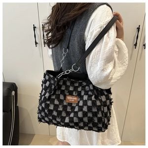 Detail of checkered tote bag with frayed edges and leather metal chain shoulder strap