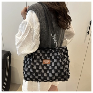Detail of denim checkerboard shoulder bag with frayed edges and silver chain strap