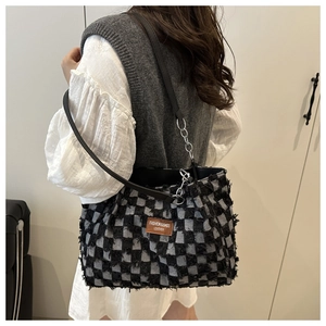 Detail of checkered denim tote bag featuring frayed edges and silver chain strap details