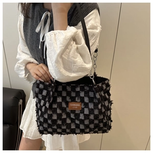 Detail of checkered tote bag with frayed edges, leather tag and chain shoulder strap