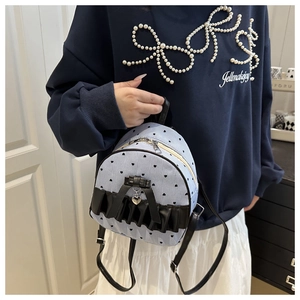 Detail of blue striped mini backpack with black ribbon bow and silver heart charm