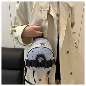 Close-up of mini backpack with blue white stripes, black heart patterns and bow detail