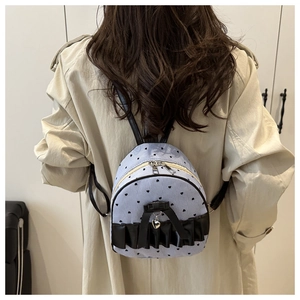 Detail of light blue striped backpack with black heart prints and ribbon accent