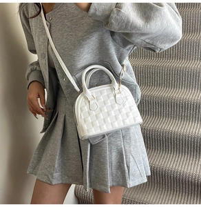 Chic white shell bag with embossed texture shown being worn on shoulder with strap