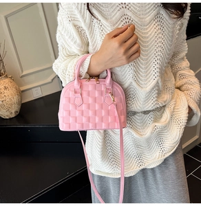 Macro detail of glossy pink embossed checkered texture and golden zipper on shell bag