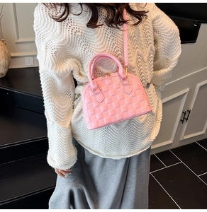 Pink patent leather shell bag with embossed checkerboard texture shown on a model