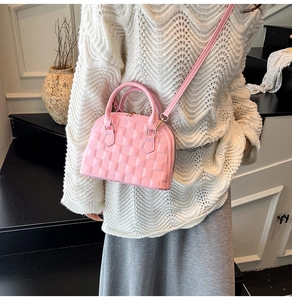 Detail of pink shell handbag featuring premium woven texture and gold-tone metal hardware
