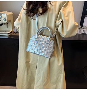 Street style view of a silver shell dome bag with quilted texture and long shoulder strap