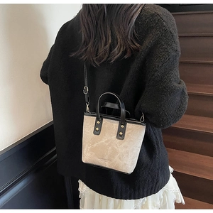 Chic khaki tote bag with black trim shown as a crossbody on a stylish model