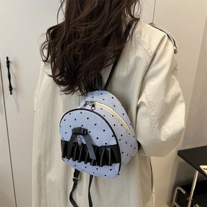Mini striped backpack with black hearts, bow, and ruffles shown on model's shoulder