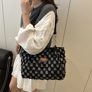 Retro checkered tote bag with fringe texture and metal chain strap worn by a model