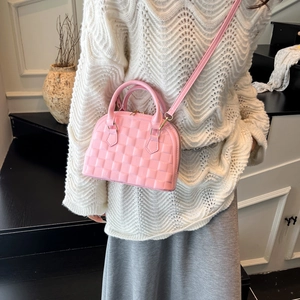 Chic pink shell-shaped crossbody handbag with woven texture shown on a female model