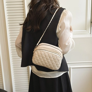 Quilted beige crossbody bag with three zip compartments and metal chain strap