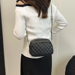 Schicke schwarze Stepptasche mit goldener Kette am Modell, stilvolle quadratische Tasche