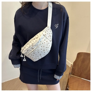 Détail d'un sac bandoulière crème avec motifs cœurs et papillons et sangle blanche