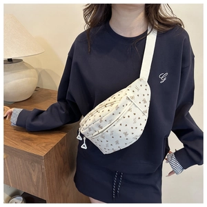 Détail d'un sac bandoulière en velours côtelé blanc à motifs porté par un mannequin