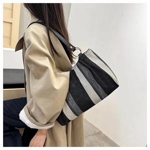 Close-up of black and white striped canvas tote bag with black leather shoulder strap