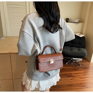 Sac bandoulière marron à motif crocodile porté par un mannequin, vue de côté
