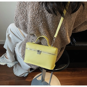 Dettaglio di una borsa a scatola giallo brillante in pelle martellata con zip argentata