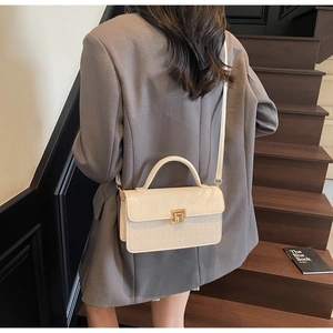 Close-up of cream crocodile pattern bag with gold square lock and elegant texture