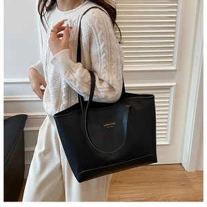 Sac cabas noir minimaliste avec lettrage doré présenté dans un décor de style de vie