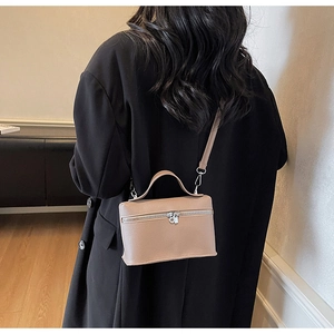 Dettaglio della borsa a tracolla in pelle martellata marrone chiaro su blazer nero