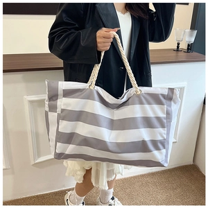 Detail of grey and white striped canvas tote bag with thick cream rope handles