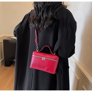 Modella che indossa una borsa squadrata rossa testurizzata con un cappotto nero